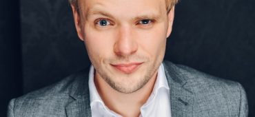 Christian im Anzug mit kritisch hochgezogener Augenbraue